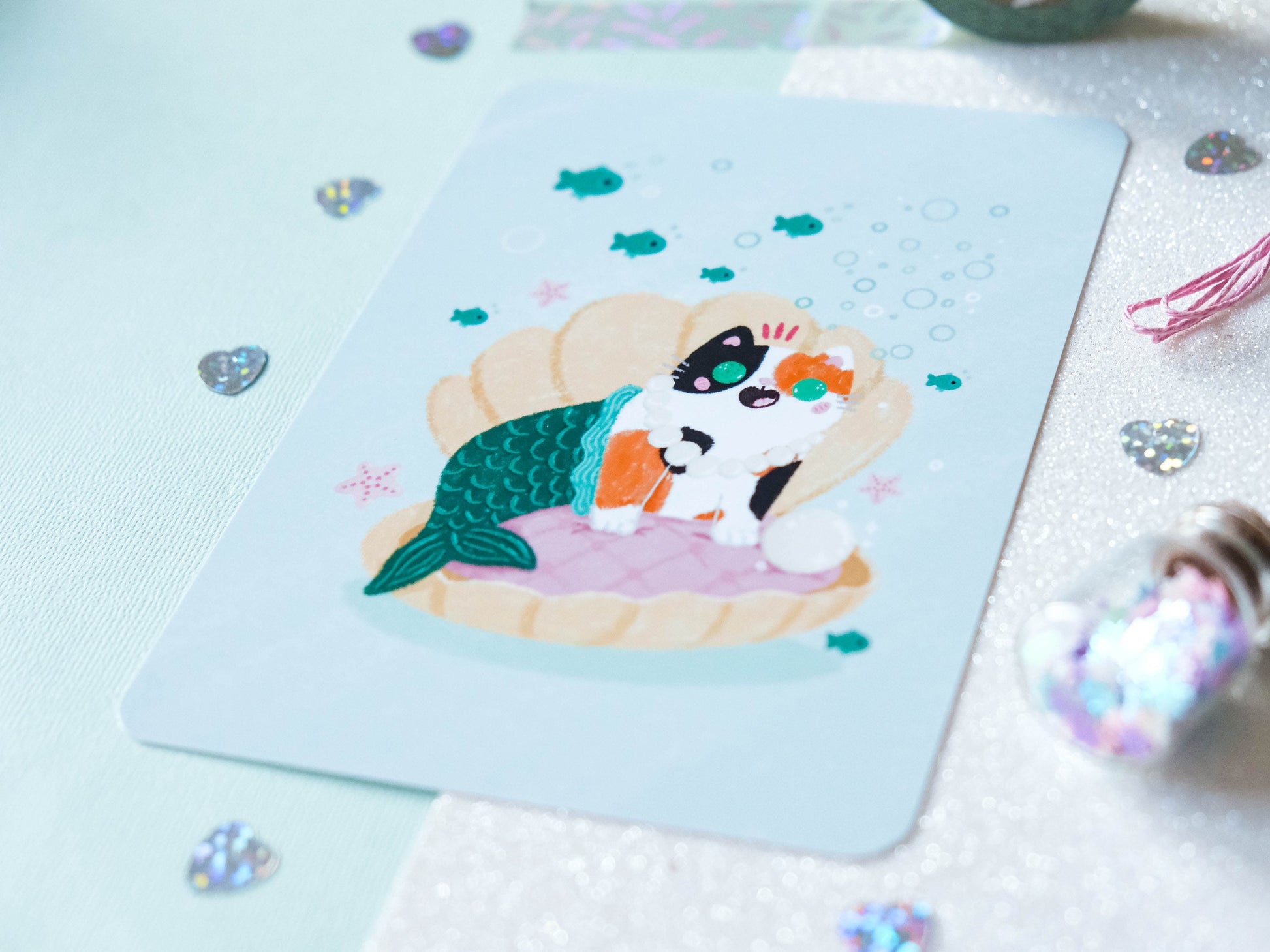 Illustration format carte A6 avec un chat calico sirène dans un coquillage avec une perle parfaite pour offrir ou décorer son intérieur