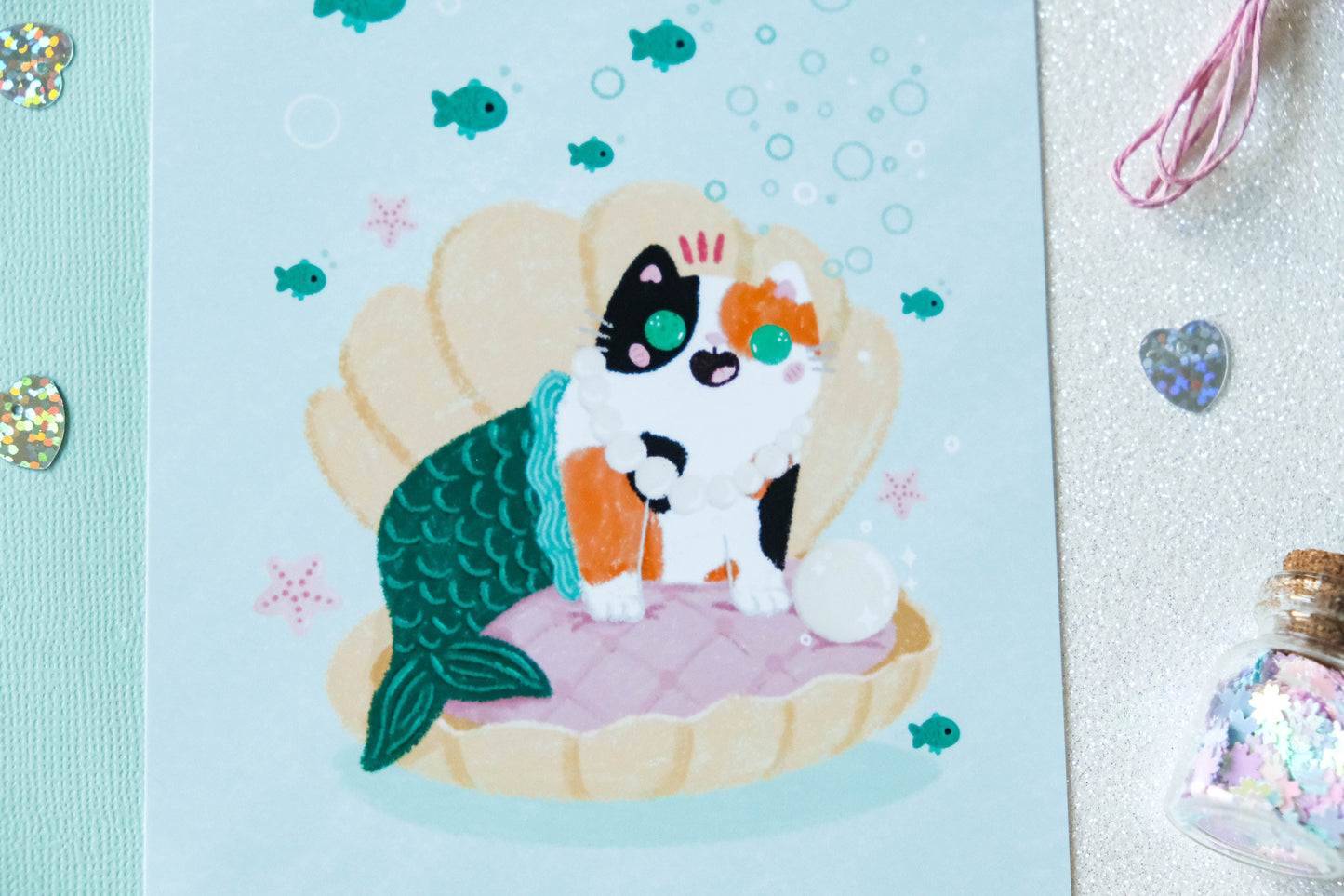 Illustration format carte A6 avec un chat calico sirène dans un coquillage avec une perle parfaite pour offrir ou décorer son intérieur